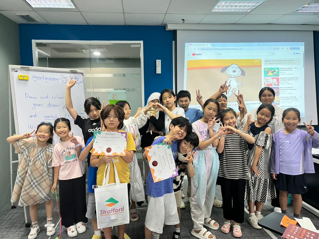 Children happily posing with their certificates while learning English at a summer camp in Malaysia